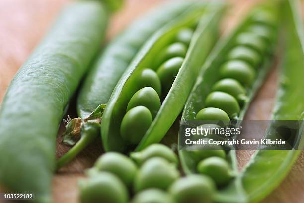 peas on a chopping board - pea pod stock pictures, royalty-free photos & images