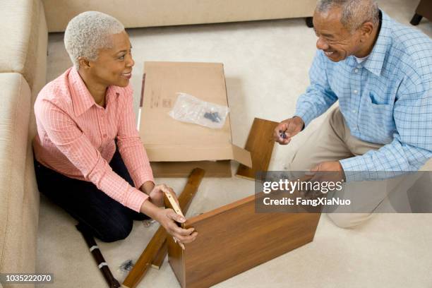 african couple assembling shelf - building shelves stock pictures, royalty-free photos & images