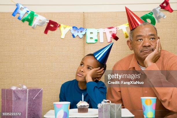 african boy with grandfather and cupcake at birthday party - sad birthday stock pictures, royalty-free photos & images