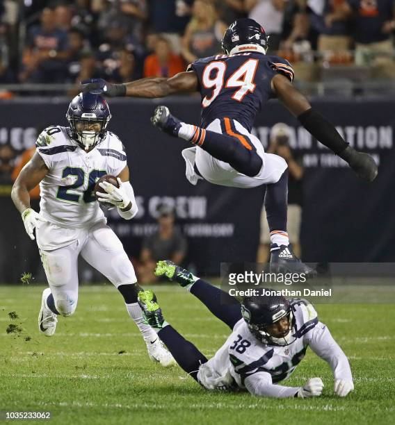 Rashaad Penny of the Seattle Seahawks rushes as Tevon Mutcherson knocks Leonard Floyd of the Chicago Bears into the air at Soldier Field on September...