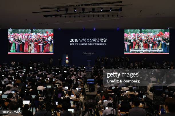 Members of the media watch screens showing a broadcast, featuring North Korean people welcoming South Korean President Moon Jae-in at Pyongyang Sunan...