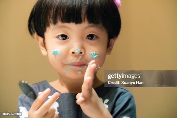 cute little girl is smiling, looking at camera and has whipped cream on her face. - whip stock pictures, royalty-free photos & images