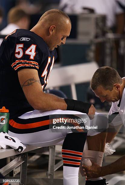 Trainer tapes ice to the leg of Brian Urlacher of the Chicago Bears who was injured in the first series against the Oakland Raiders during a...