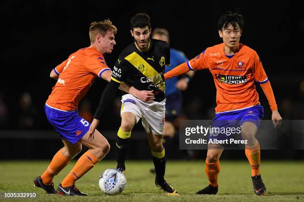 Andrew Cartanos of Heidelberg United dribbles past Tommy Jarrard and Danny Kim of Lions FC during the NPL Semi Final match between Lions FC and...