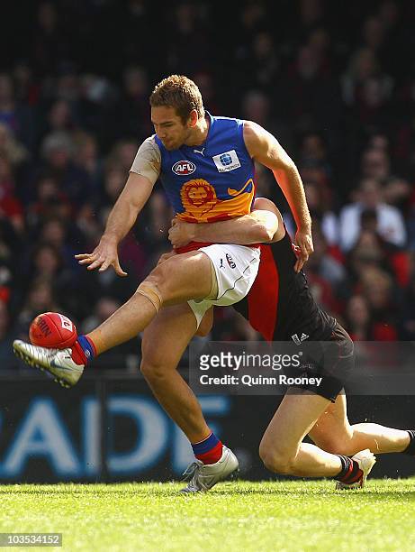 Jared Brennan of the Lions kicks whilst being tackled during the round 21 AFL match between the Essendon Bombers and the Brisbane Lions at Etihad...