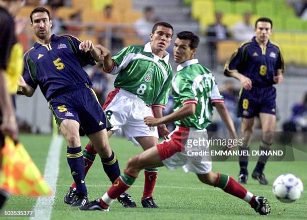 Australia's Tony Vidmar passes the ball despite pressure from Mexico's Juan Pablo Rodriguez and Jared Borgetti, 30 May 2001, during their group A...