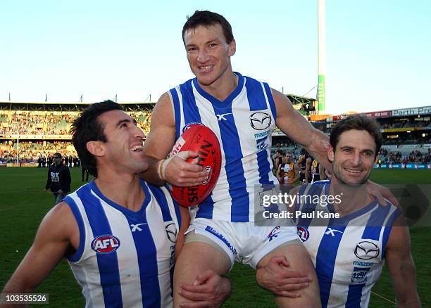 Brent Harvey of the Kangaroos is chaired from the ground by team mates Michael Firrito and Brady Rawlings after playing his 300th game during the...
