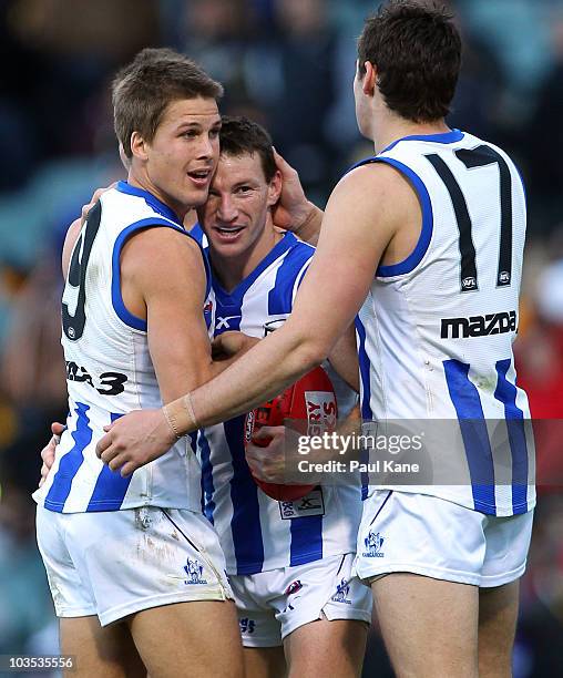 Brent Harvey of the Kangaroos celebrates with Andrew Swallow and Nathan Grima after playing his 300th game during the round 21 AFL match between the...