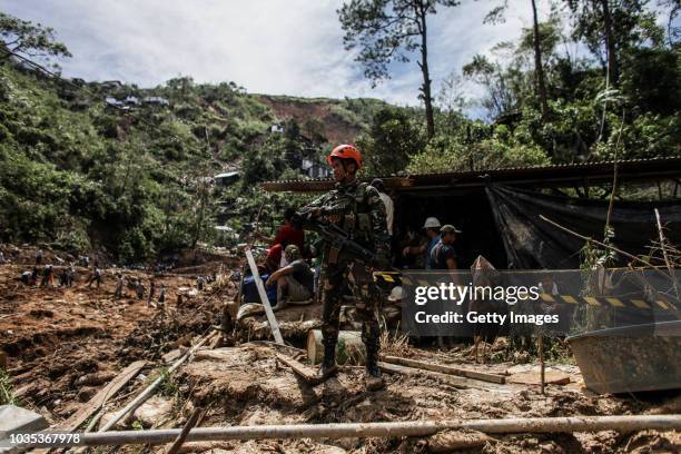 Soldier stand guard as rescuers dig at the site where people were believed to have been buried by a landslide on September 18, 2018 in in Itogon,...