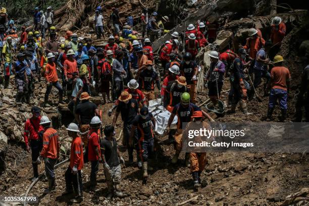 Filipino rescuers carry a body of a person inside a body bag at the site where people were believed to have been buried by a landslide on September...