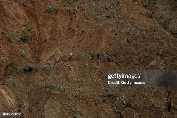 Residents walk at the site where people were believed to have been buried by a landslide on September 18, 2018 in in Itogon, Benguet province,...