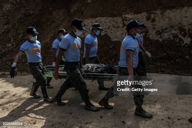 Filipino rescuers carry a body of a person inside a body bag at the site where people were believed to have been buried by a landslide on September...