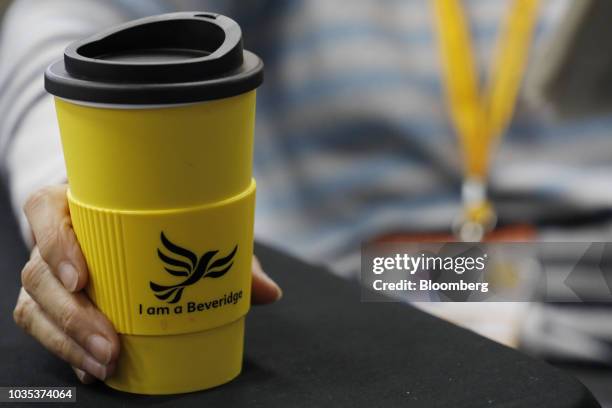 Delegate holds a yellow promotional cup decorated with the phrase 'I am a Beveridge' at the Liberal Democrat Party annual conference in Brighton,...