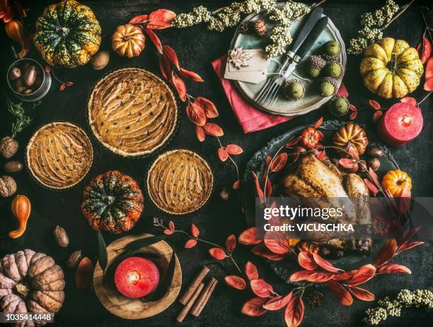 thanksgiving day dinner table with pumpkin pie, roasted turkey and festive autumn decoration and candles - friendsgiving stock pictures, royalty-free photos & images