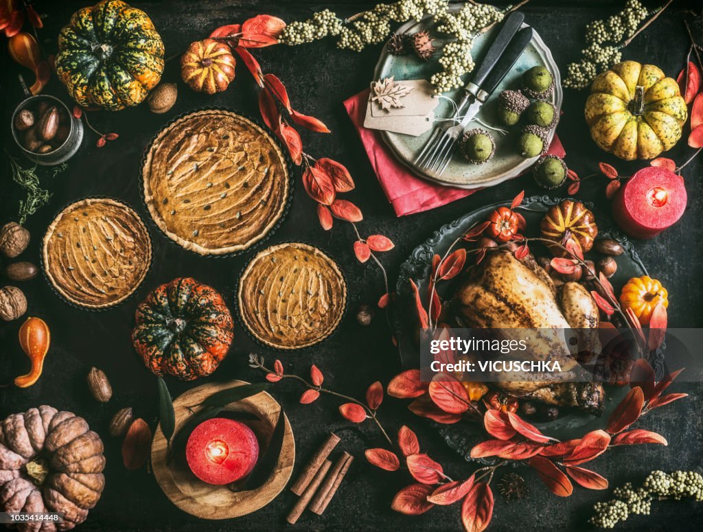 Thanksgiving day dinner table with pumpkin pie, roasted turkey and festive autumn decoration and candles