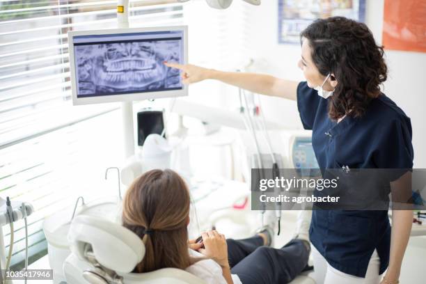 dentista donna che parla con la sua paziente nell'ufficio del dentista - ortodonzia foto e immagini stock