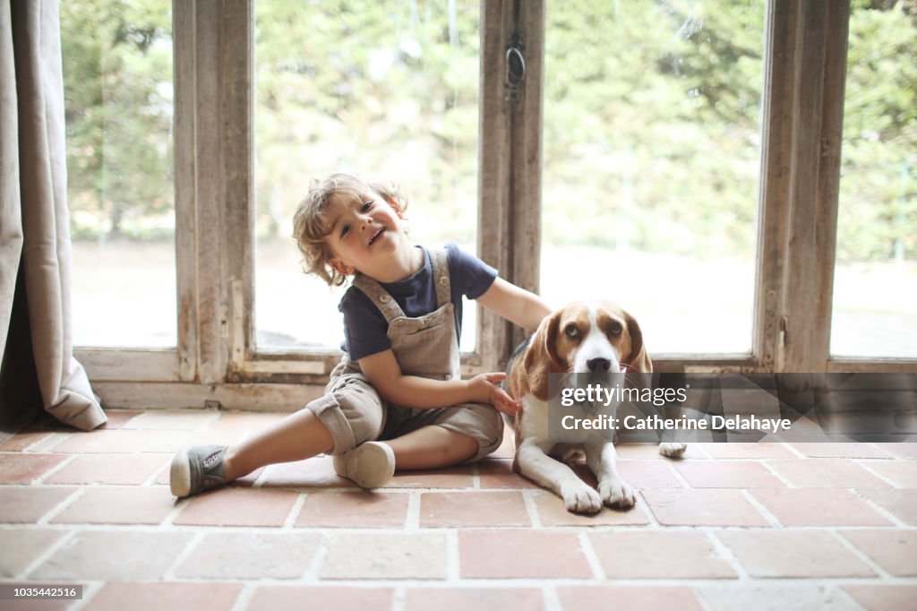 A 3 years old boy and his dog at home