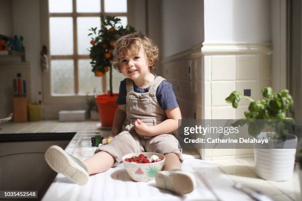 a 3 years old boy eating fruits in the kitchen - 2 3 years foto e immagini stock