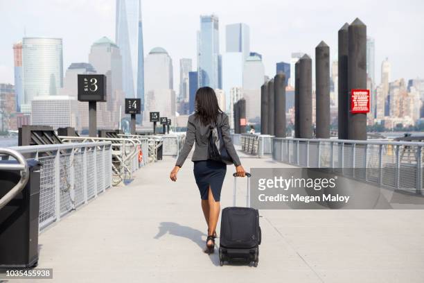 businesswoman with wheeled luggage on ferry pier - commuter ferry stock pictures, royalty-free photos & images