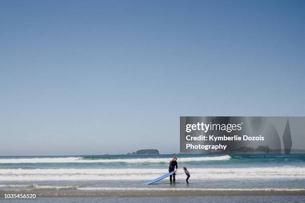 father and child surfing on beach, tofino, canada - surfer stock pictures, royalty-free photos & images