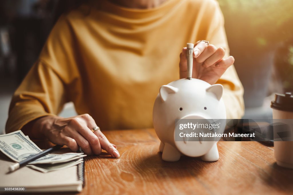 Woman hand putting money bank note dollar into piggy for saving money wealth and financial concept.
