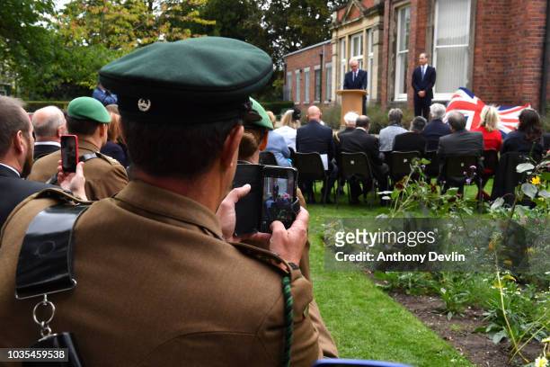Member of the armed forces takes a photograph as Prince William, Duke of Cambridge listens to a speech by Ian Austin MP before unveiling a new...