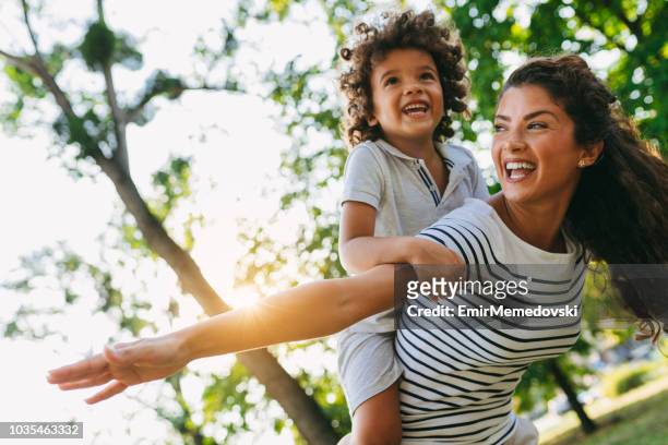 mother piggybacking son in park - carrying on shoulders stock pictures, royalty-free photos & images