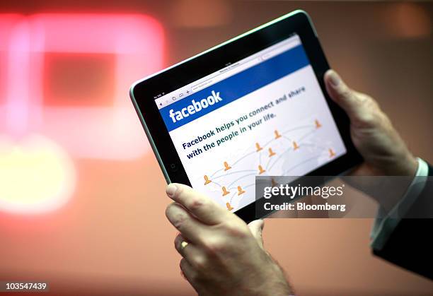 Businessman displays the Facebook Inc. Web page using an Apple iPad, made by Apple Inc. In this arranged photograph in London, U.K., on Thursday,...
