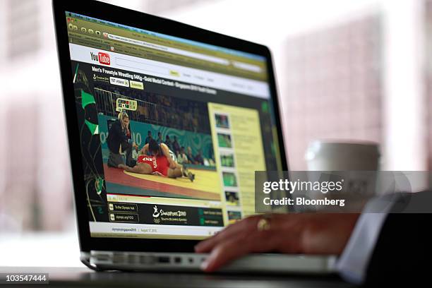 Businessman watches a video clip on Google Inc.�s YouTube website using an Apple Macbook Pro laptop computer, made by Apple Inc., in this arranged...