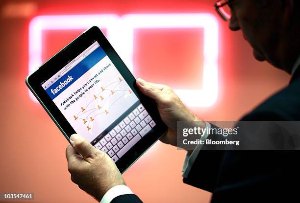 Businessman displays the Facebook Inc. Web page using an Apple iPad, made by Apple Inc. In this arranged photograph in London, U.K., on Thursday,...