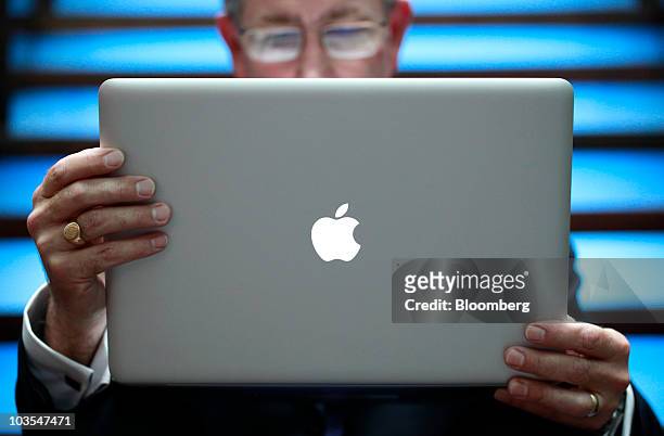 Businessman holds an Apple Macbook Pro laptop computer, made by Apple Inc., to surf the web in this arranged photograph in London, U.K., on Thursday,...