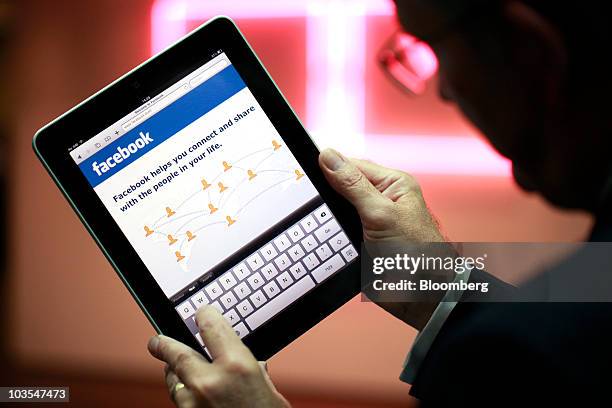 Businessman displays the Facebook Inc. Web page using an Apple iPad, made by Apple Inc. In this arranged photograph in London, U.K., on Thursday,...