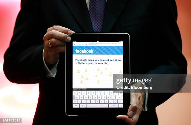 Businessman displays the Facebook Inc. Web page using an Apple iPad, made by Apple Inc. In this arranged photograph in London, U.K., on Thursday,...