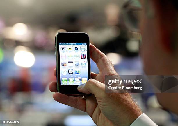 Businessman checks the application menu displayed on the screen of Apple Inc.'s Apple iPhone connected via the VodafoneUK 3G network in an arranged...