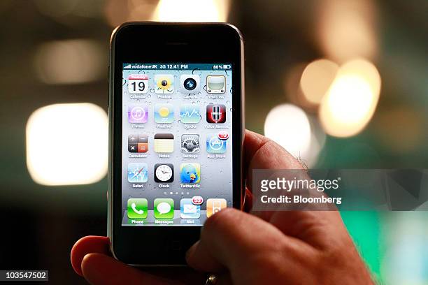 Businessman checks the application menu displayed on the screen of Apple Inc.'s Apple iPhone connected via the VodafoneUK 3G network in an arranged...