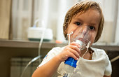 Little boy using nebulizer during inhaling therapy.