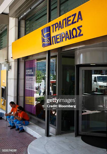 Municipal workers sit at the entrance to a Piraeus Bank SA branch in Athens, Greece, on Tuesday, Aug. 24, 2010. Greek banks are under growing...