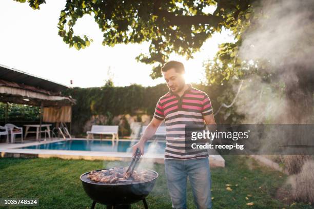 homme de cuisson de la viande sur le barbecue - barbecue photos et images de collection
