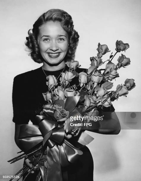 Actress Jane Powell pictured smiling while holding a large bouquet of flowers, USA, circa 1950. Powell was attending a National Flower Week event.