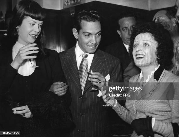 Comedian Mario Moreno , also known as Cantinflas, toasts singer Edith Piaf as he and his lady friend visit the Ciudad Luz nightclub in Paris, France,...