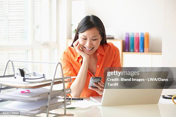 chinese businesswoman text messaging on cell phone at desk - receiving check stock pictures, royalty-free photos & images
