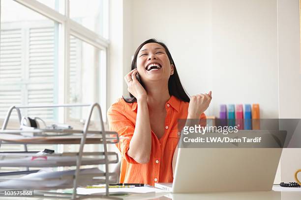 happy chinese businesswoman talking on cell phone at desk - mobile first stock pictures, royalty-free photos & images