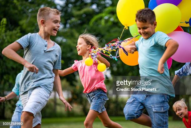 bambini felici che corrono con i palloncini - kids birthday party foto e immagini stock