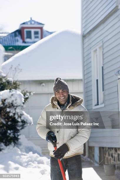 mixed race man shoveling snow off driveway - shoveling driveway stock pictures, royalty-free photos & images