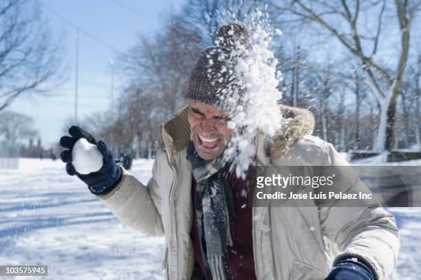 mixed race man having snowball fight - face snow stockfoto's en -beelden