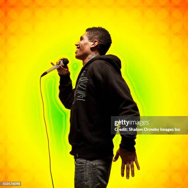 mixed race man singing into microphone - mixed race man standing studio stockfoto's en -beelden