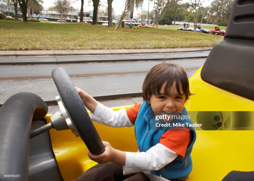Mixed race boy driving go-cart