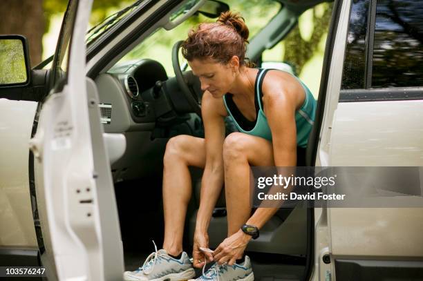 runner sitting in car tying shoes - car rent stockfoto's en -beelden