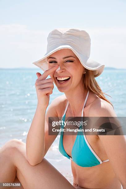 woman putting on sun lotion at the beach - putting lotion stock pictures, royalty-free photos & images