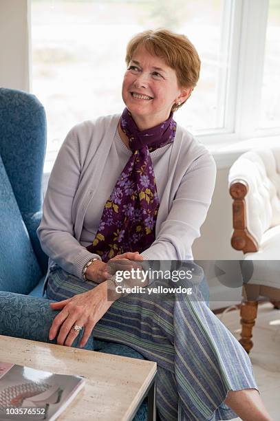 mature woman smiling in living room - new england women stock pictures, royalty-free photos & images